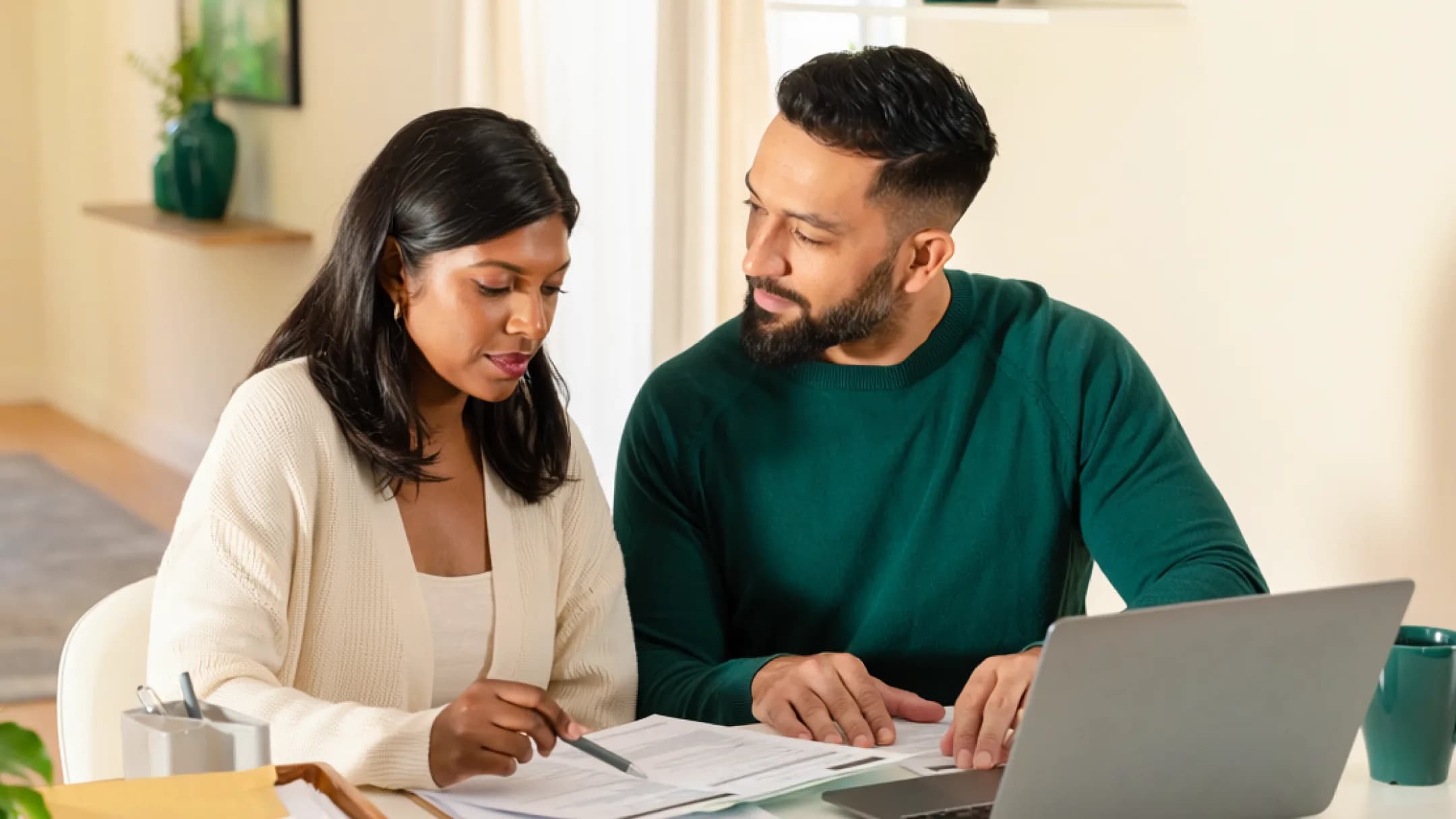 A couple reviewing E-2 visa business plan documents together at a home desk with a laptop